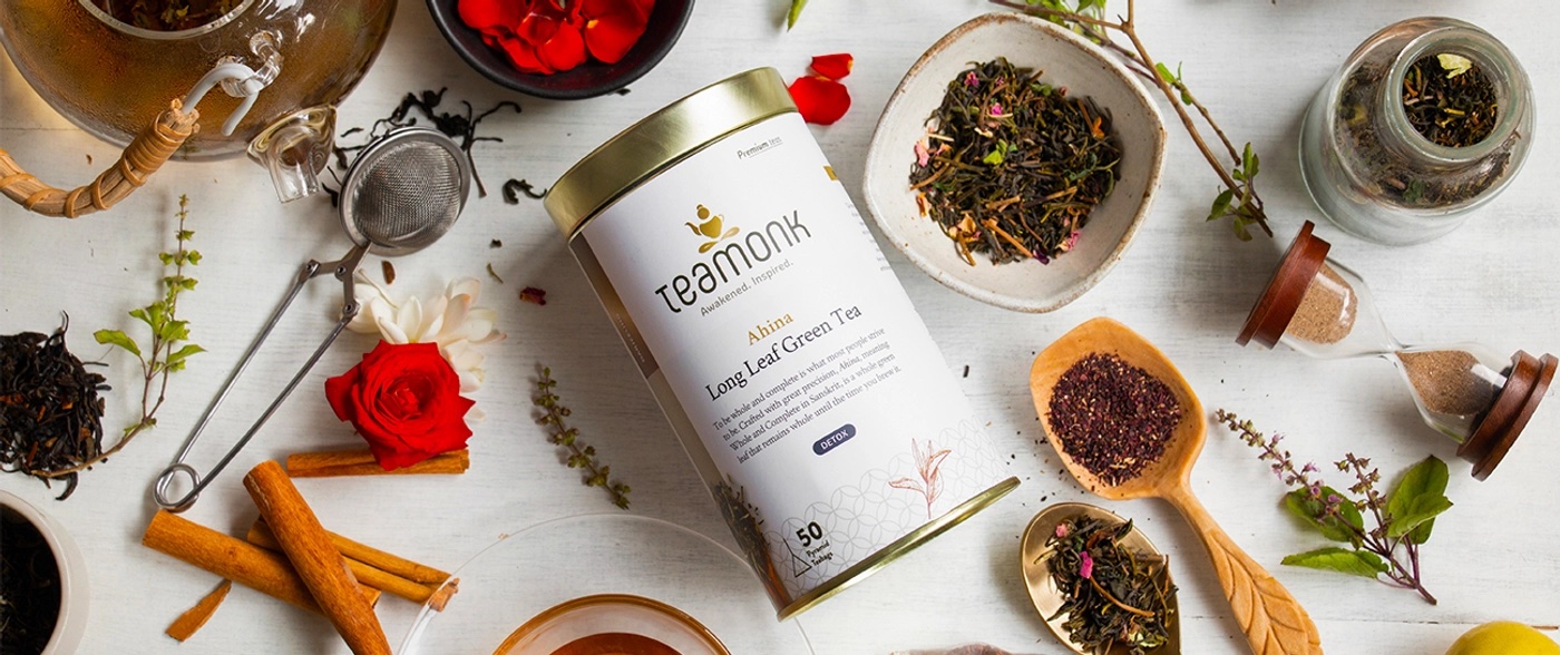 Teamonk tea products surrounded by loose tea leaves